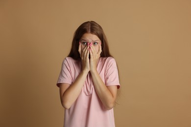 Photo of Teenage girl suffering from panic attack on beige background
