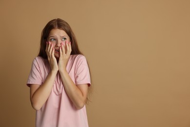 Photo of Teenage girl suffering from panic attack on beige background. Space for text