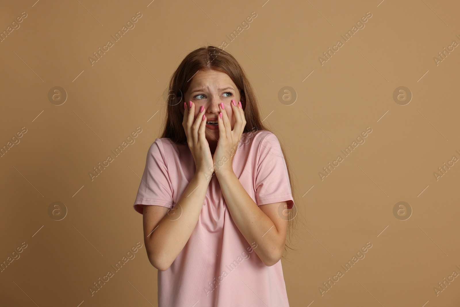 Teenage girl suffering from panic attack on beige background Photo of Teenage girl suffering from panic attack on beige background
