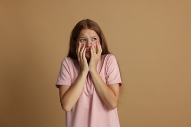 Photo of Teenage girl suffering from panic attack on beige background