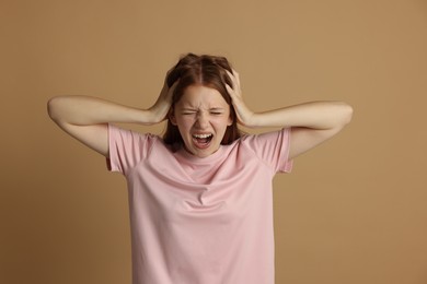 Photo of Teenage girl suffering from panic attack on beige background