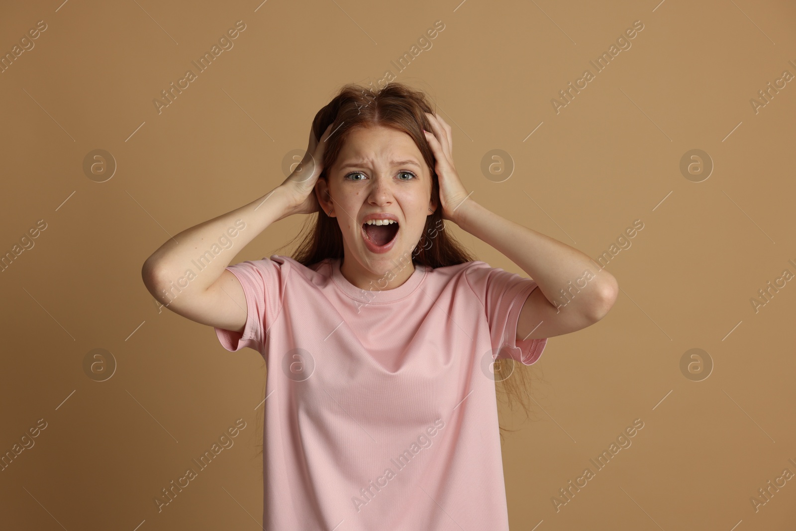 Photo of Teenage girl suffering from panic attack on beige background