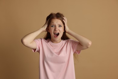 Photo of Teenage girl suffering from panic attack on beige background