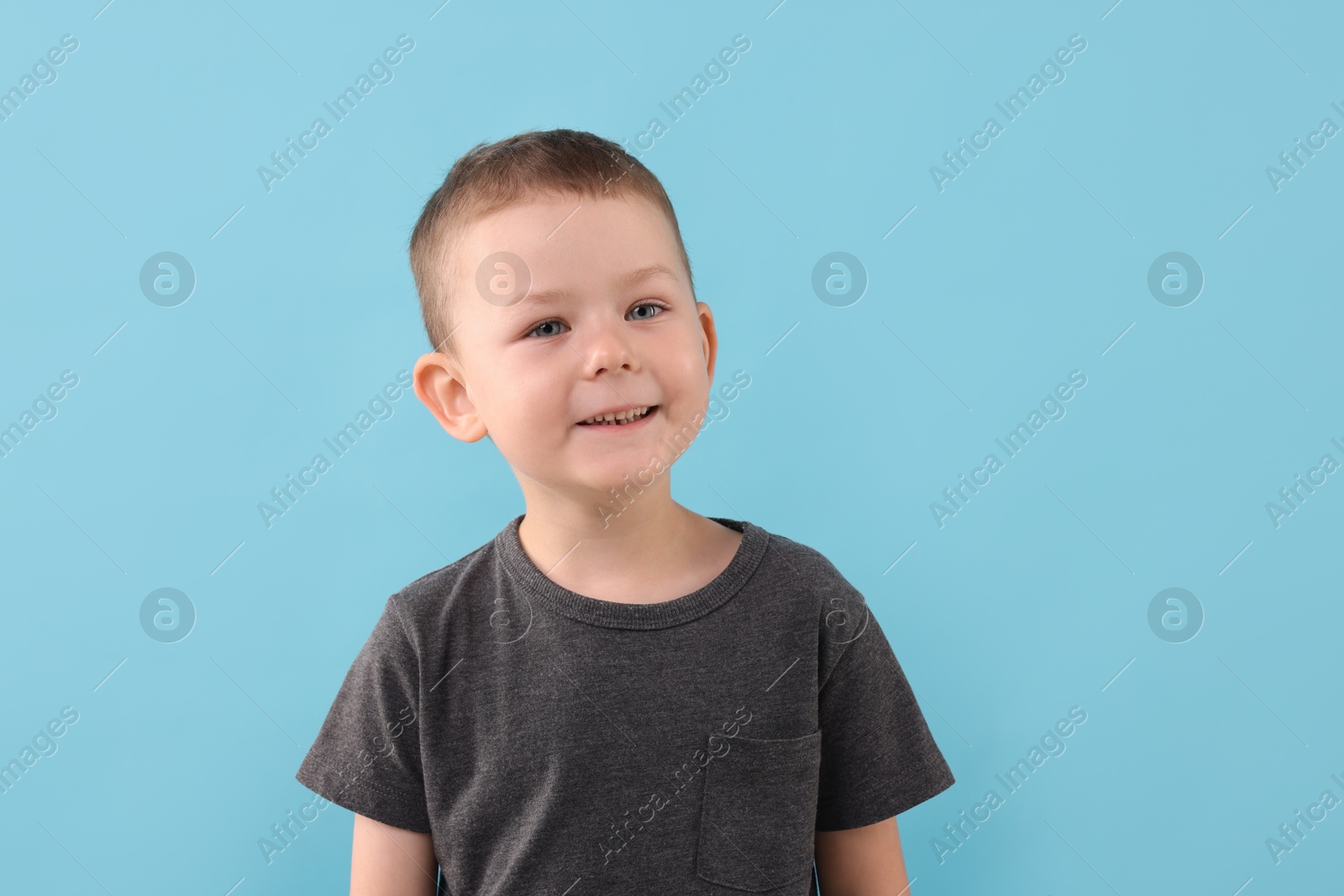 Portrait of smiling boy on light blue background Photo of Portrait of smiling boy on light blue background