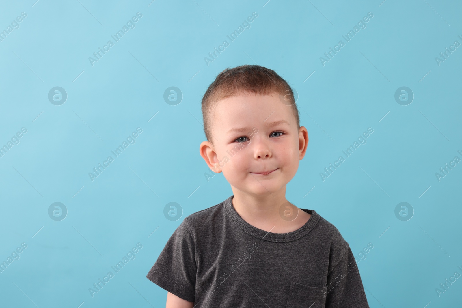 Portrait of smiling boy on light blue background Photo of Portrait of smiling boy on light blue background
