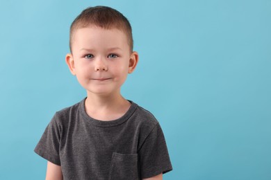 Photo of Portrait of smiling boy on light blue background. Space for text