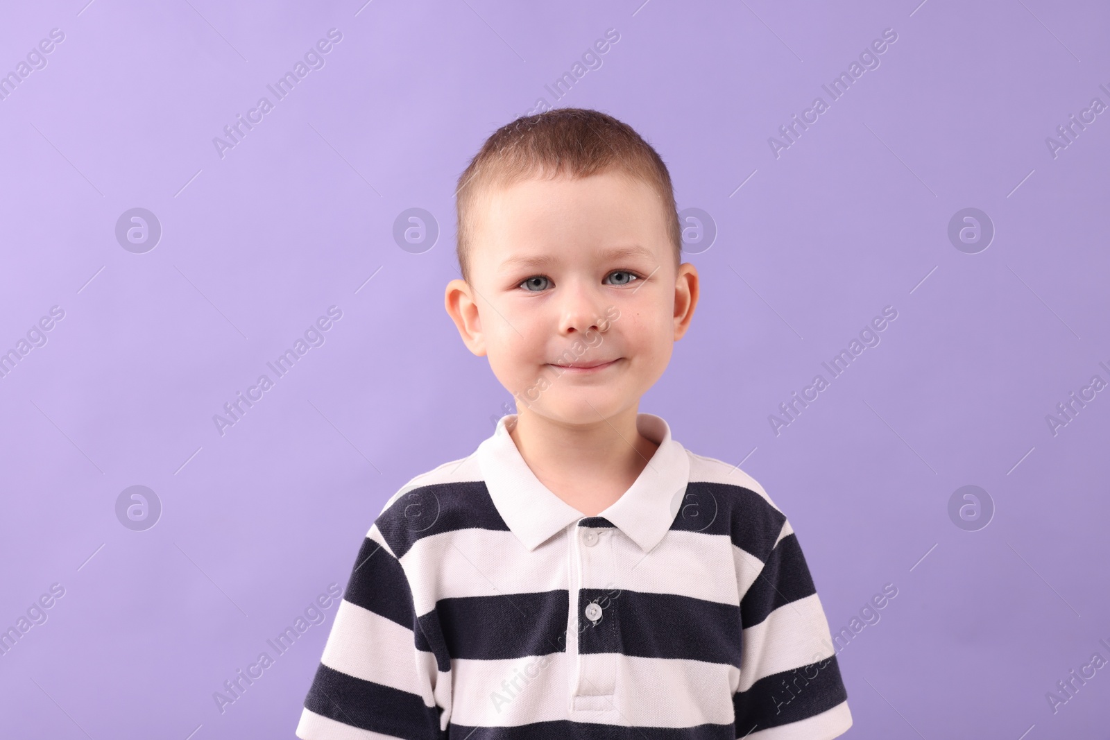 Photo of Portrait of smiling boy on violet background