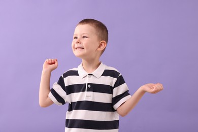 Photo of Cute little boy laughing on violet background