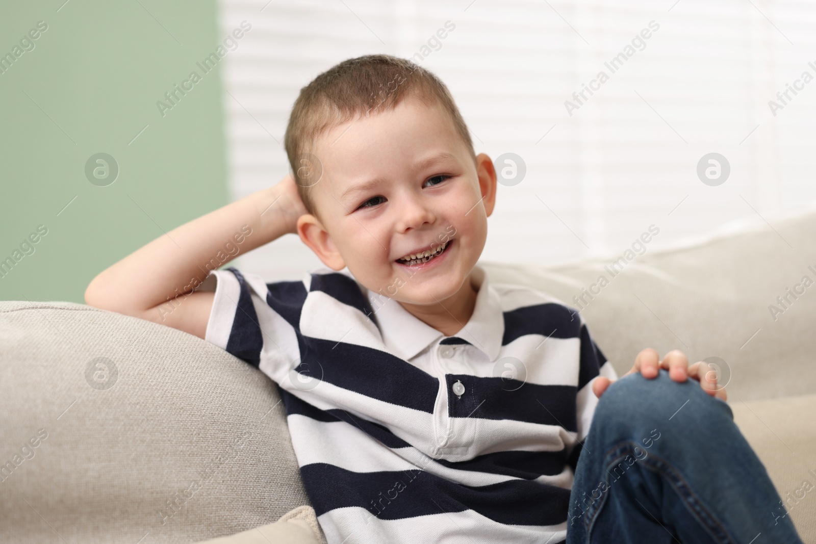 Cute little boy laughing on sofa at home Photo of Cute little boy laughing on sofa at home