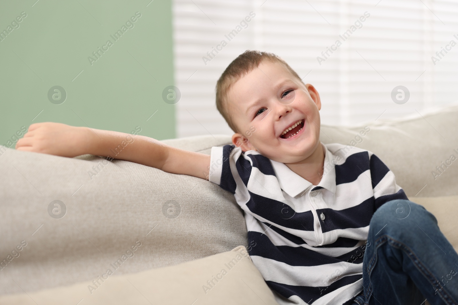 Cute little boy laughing on sofa at home Photo of Cute little boy laughing on sofa at home