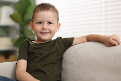 Photo of Smiling little boy on sofa at home