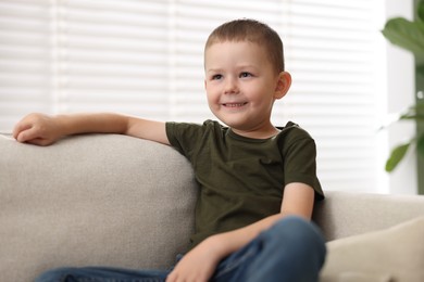 Photo of Smiling little boy on sofa at home