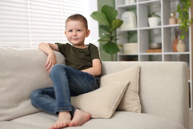 Photo of Smiling little boy on sofa at home. Space for text