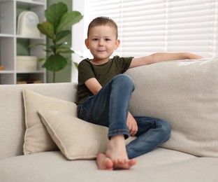 Photo of Smiling little boy on sofa at home