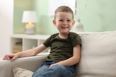 Photo of Smiling little boy on sofa at home