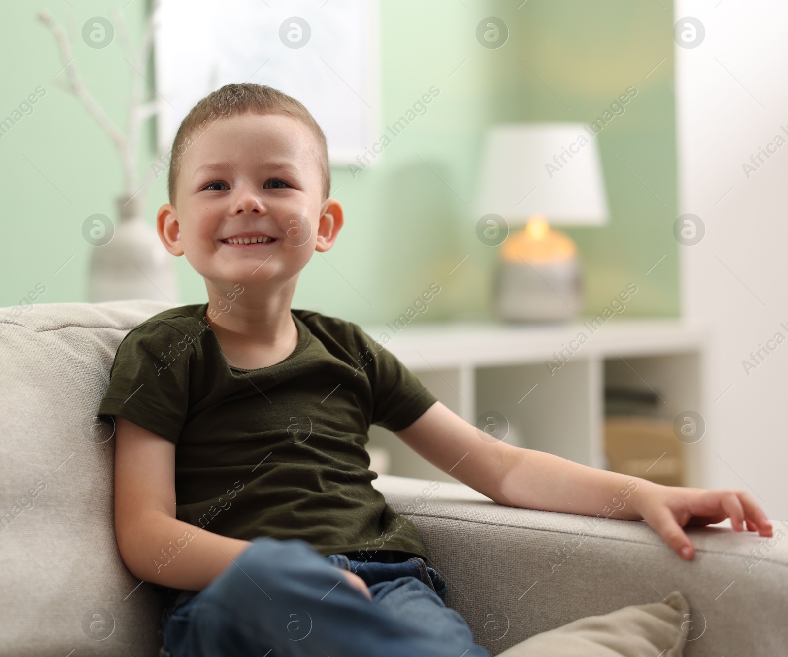 Smiling little boy on sofa at home. Space for text Photo of Smiling little boy on sofa at home. Space for text