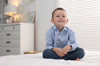 Photo of Smiling little boy on bed at home