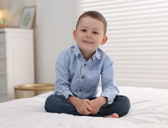 Photo of Smiling little boy on bed at home