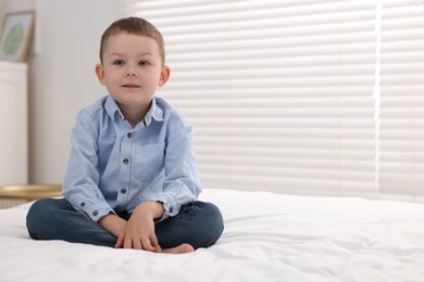 Photo of Smiling little boy on bed at home. Space for text
