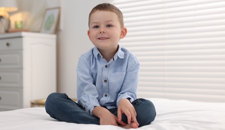 Photo of Smiling little boy on bed at home