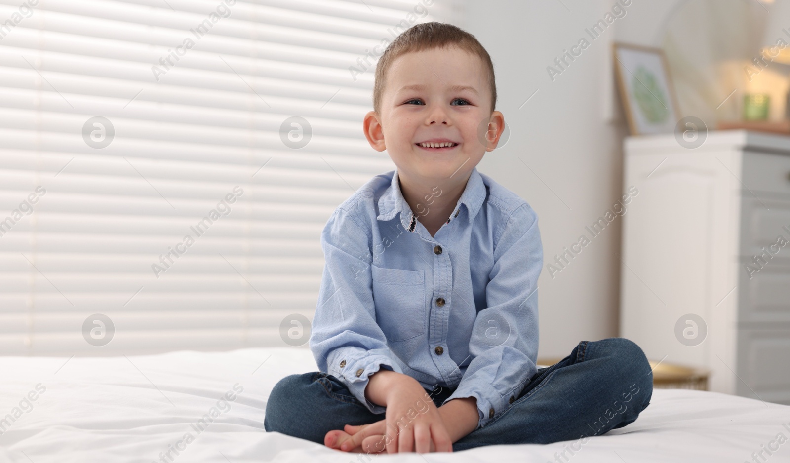 Photo of Smiling little boy on bed at home. Space for text