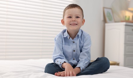 Photo of Smiling little boy on bed at home. Space for text