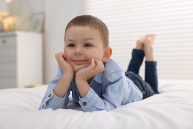 Photo of Smiling little boy on bed at home