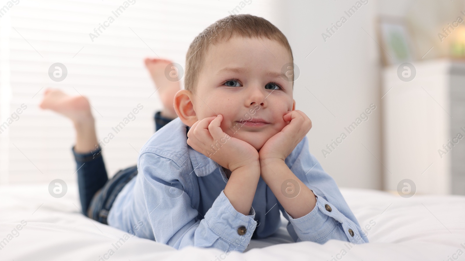 Photo of Smiling little boy on bed at home