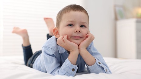 Photo of Smiling little boy on bed at home
