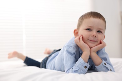 Photo of Smiling little boy on bed at home. Space for text