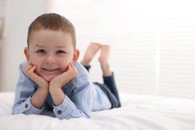 Photo of Smiling little boy on bed at home. Space for text