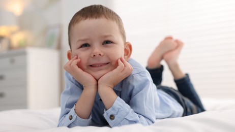 Photo of Smiling little boy on bed at home