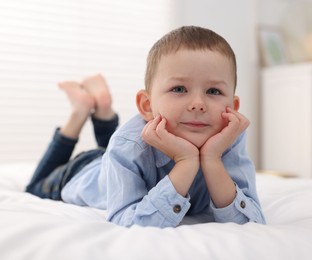 Photo of Smiling little boy on bed at home