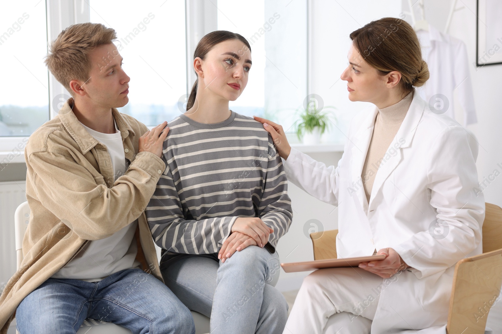 In vitro fertilization (IVF). Doctor supporting upset couple during visit in reproductive clinic Photo of In vitro fertilization (IVF). Doctor supporting upset couple during visit in reproductive clinic