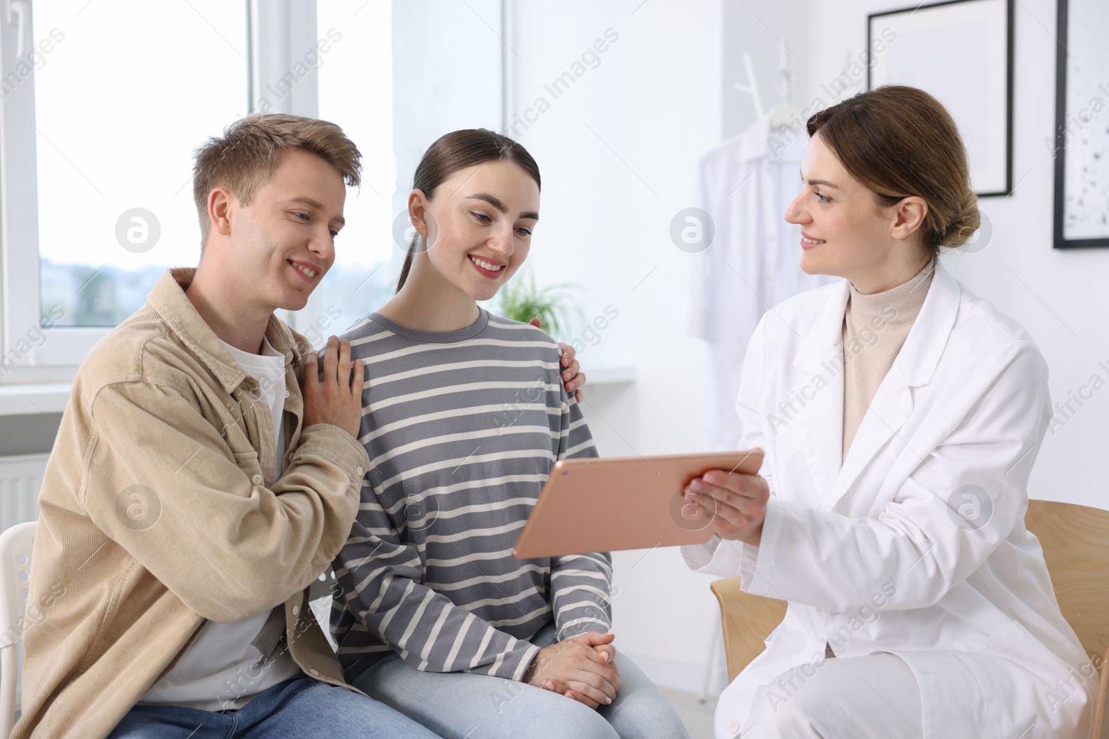 In vitro fertilization (IVF). Doctor showing couple good results on tablet in reproductive clinic Photo of In vitro fertilization (IVF). Doctor showing couple good results on tablet in reproductive clinic