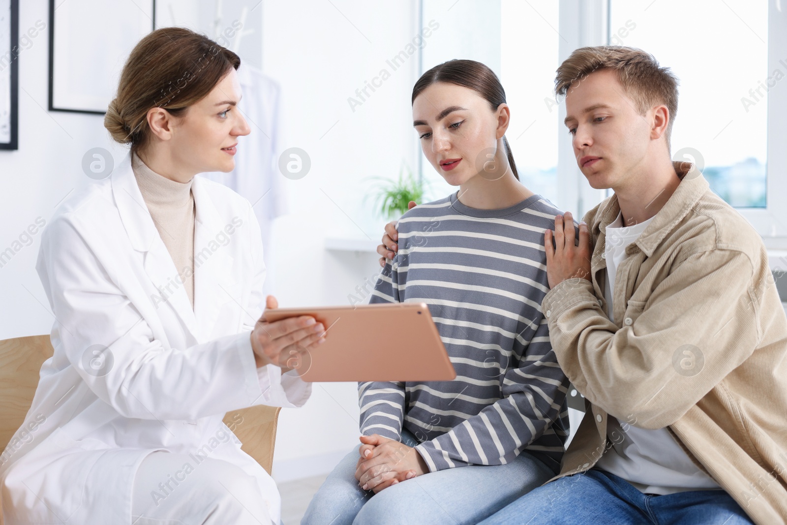 In vitro fertilization (IVF). Doctor showing couple results on tablet in reproductive clinic Photo of In vitro fertilization (IVF). Doctor showing couple results on tablet in reproductive clinic