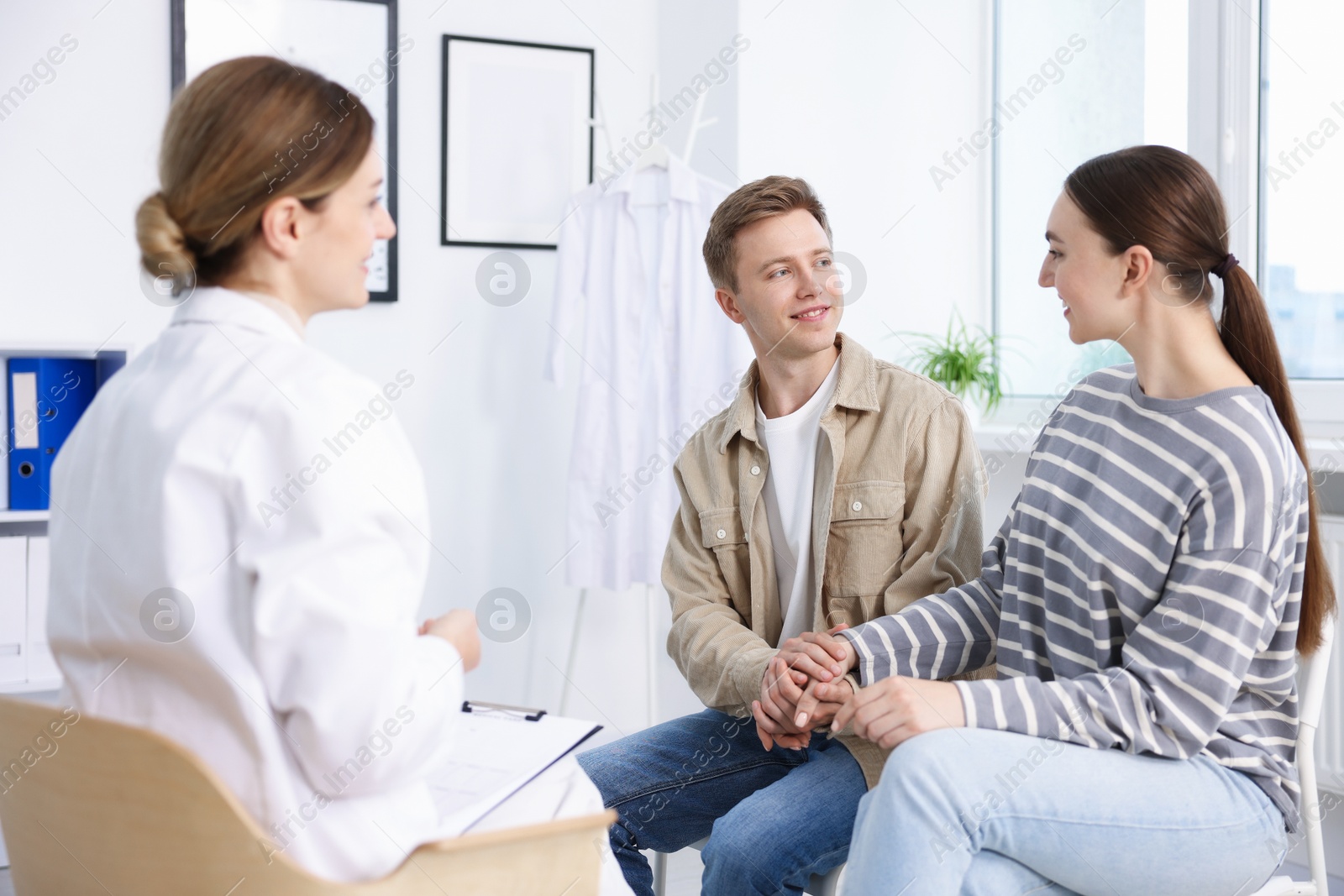 Photo of In vitro fertilization (IVF). Happy couple having appointment with doctor in reproductive clinic