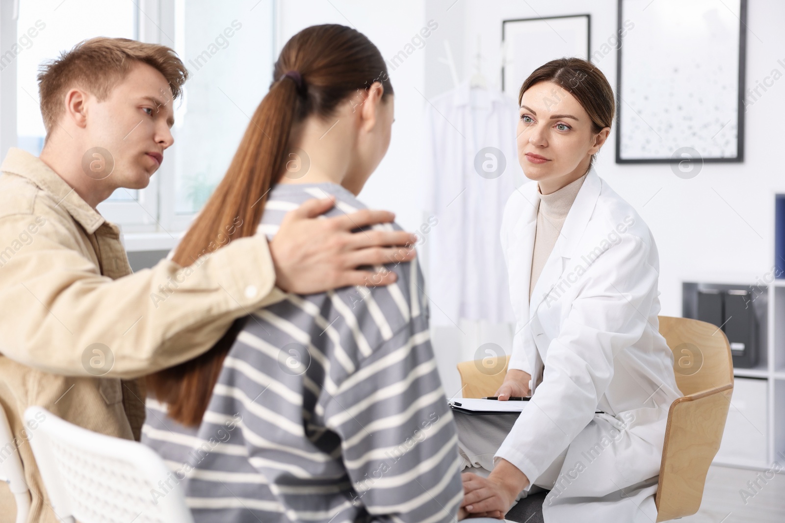 In vitro fertilization (IVF). Doctor supporting upset couple during visit in reproductive clinic Photo of In vitro fertilization (IVF). Doctor supporting upset couple during visit in reproductive clinic
