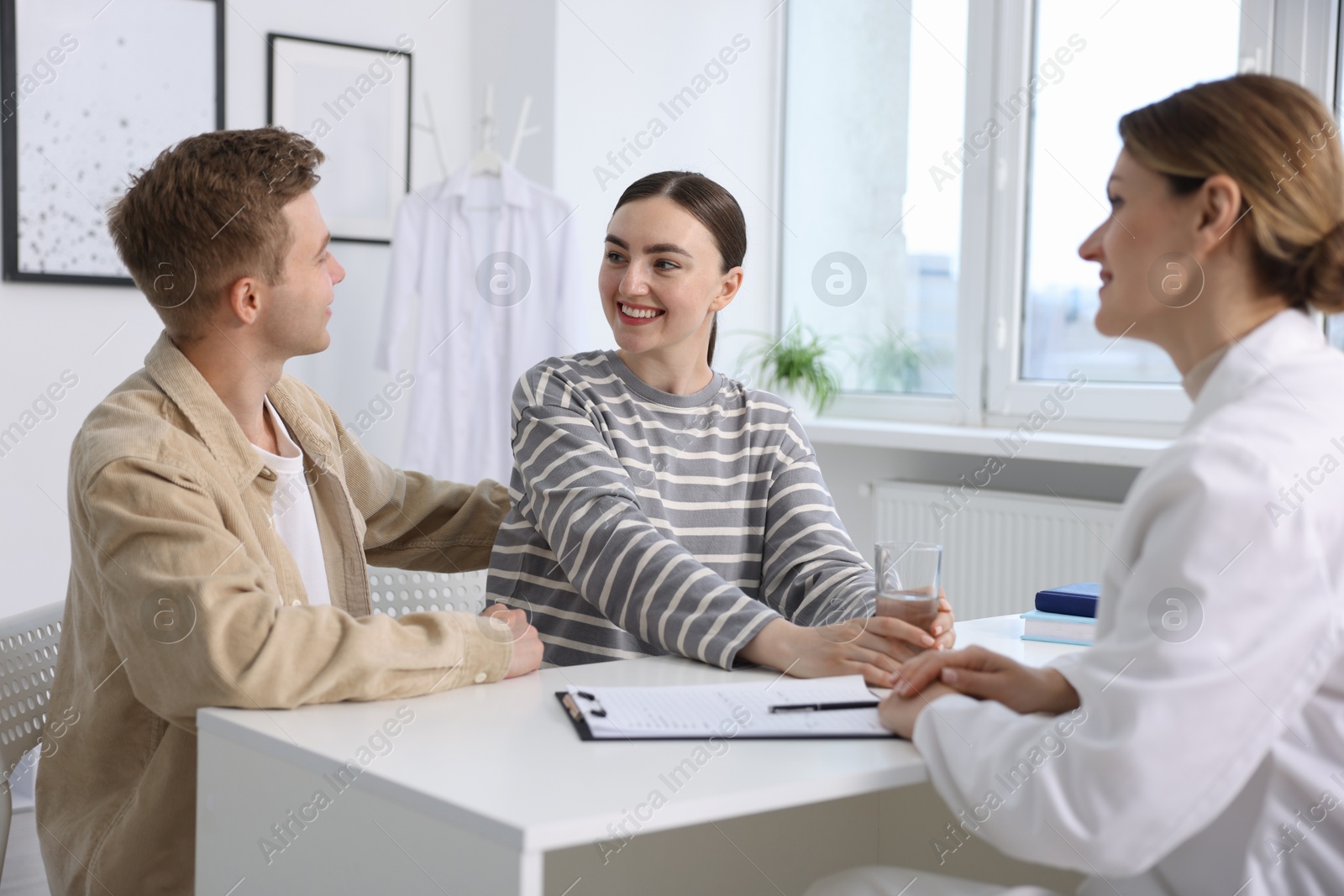 Photo of In vitro fertilization (IVF). Happy couple having appointment with doctor in reproductive clinic
