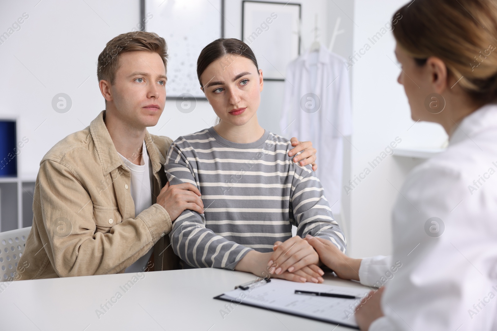 In vitro fertilization (IVF). Doctor supporting upset couple during visit in reproductive clinic Photo of In vitro fertilization (IVF). Doctor supporting upset couple during visit in reproductive clinic
