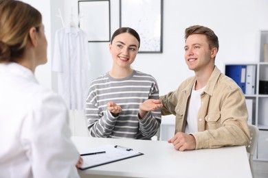 Photo of In vitro fertilization (IVF). Happy couple having appointment with doctor in reproductive clinic