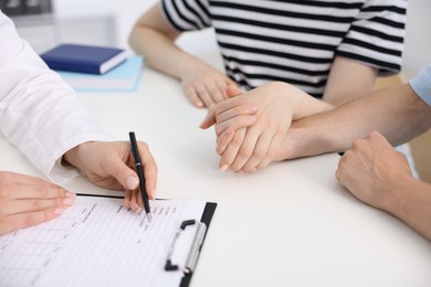 Photo of In vitro fertilization (IVF). Couple holding hands during appointment with doctor in reproductive clinic, closeup