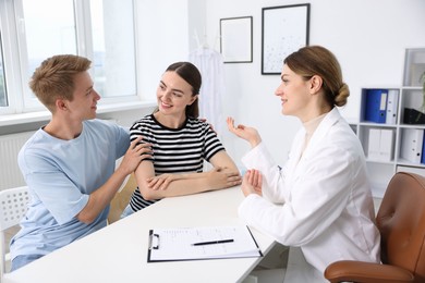 Photo of In vitro fertilization (IVF). Happy couple having appointment with doctor in reproductive clinic