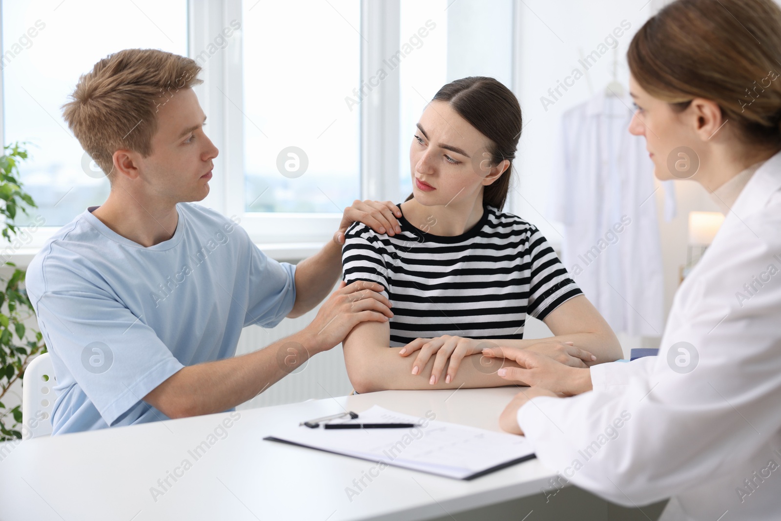 In vitro fertilization (IVF). Doctor supporting upset couple during visit in reproductive clinic Photo of In vitro fertilization (IVF). Doctor supporting upset couple during visit in reproductive clinic