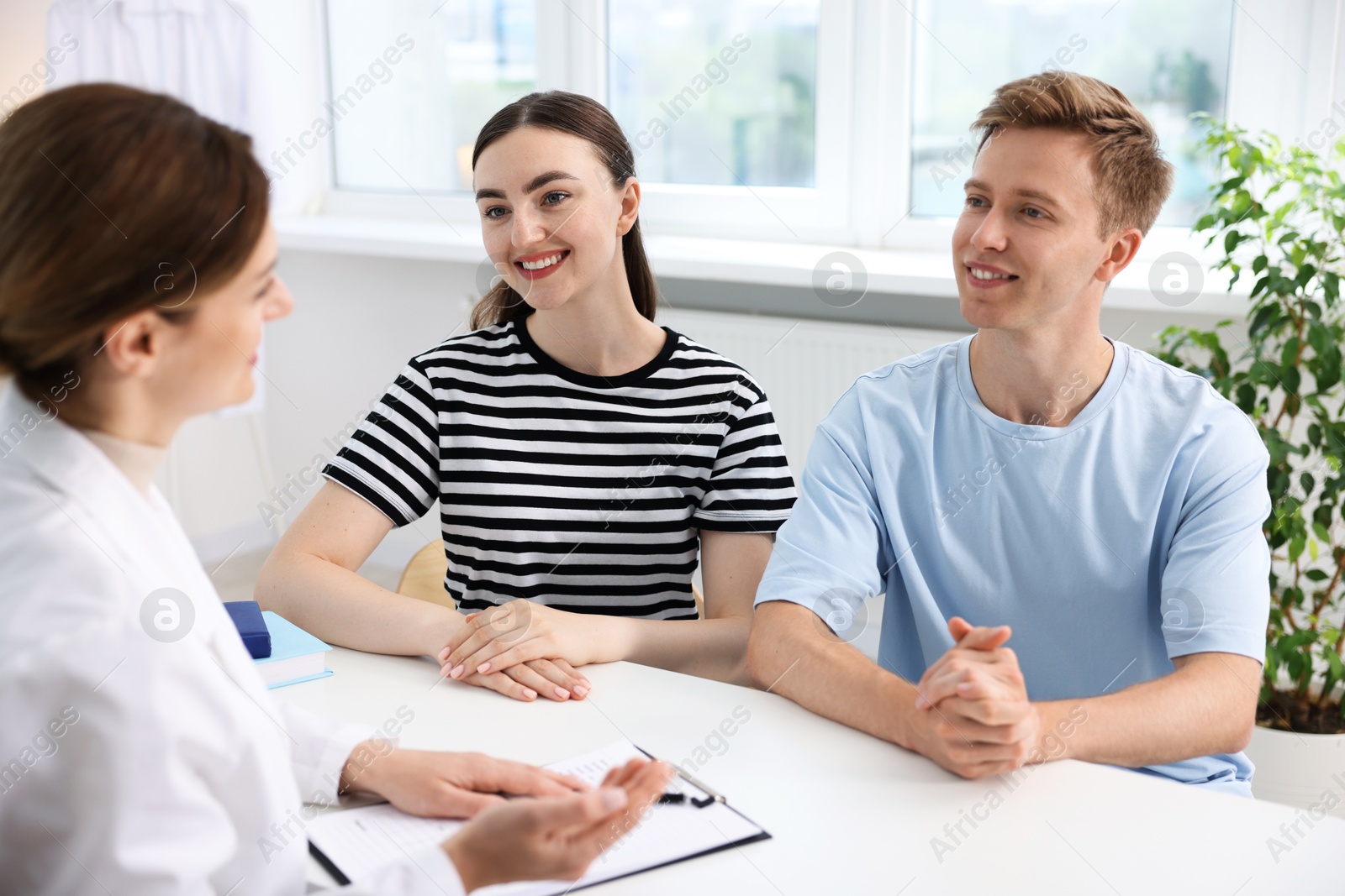 In vitro fertilization (IVF). Happy couple having appointment with doctor in reproductive clinic Photo of In vitro fertilization (IVF). Happy couple having appointment with doctor in reproductive clinic