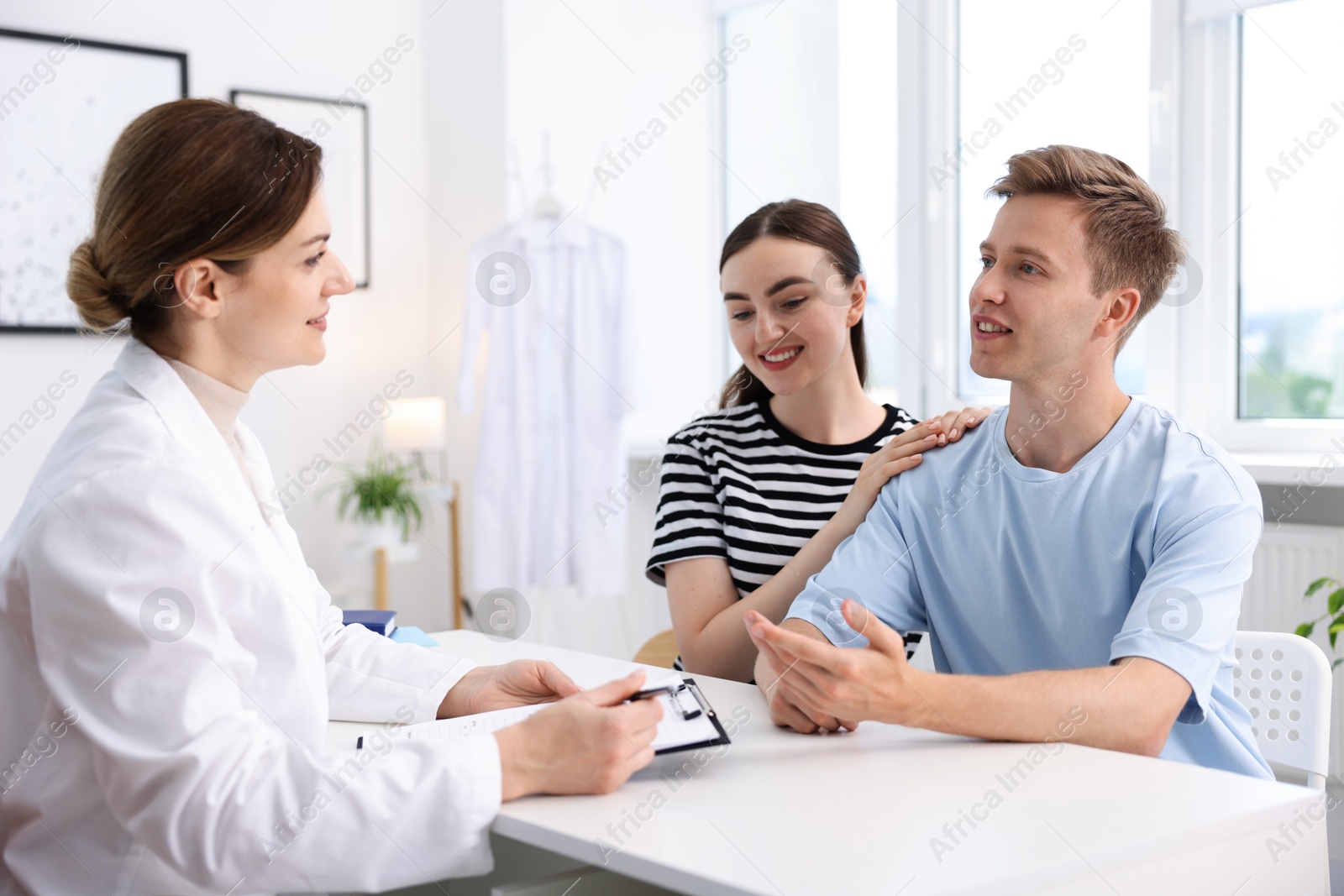 Photo of In vitro fertilization (IVF). Happy couple having appointment with doctor in reproductive clinic
