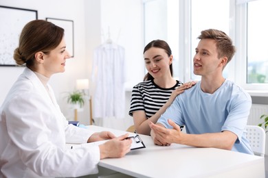 Photo of In vitro fertilization (IVF). Happy couple having appointment with doctor in reproductive clinic