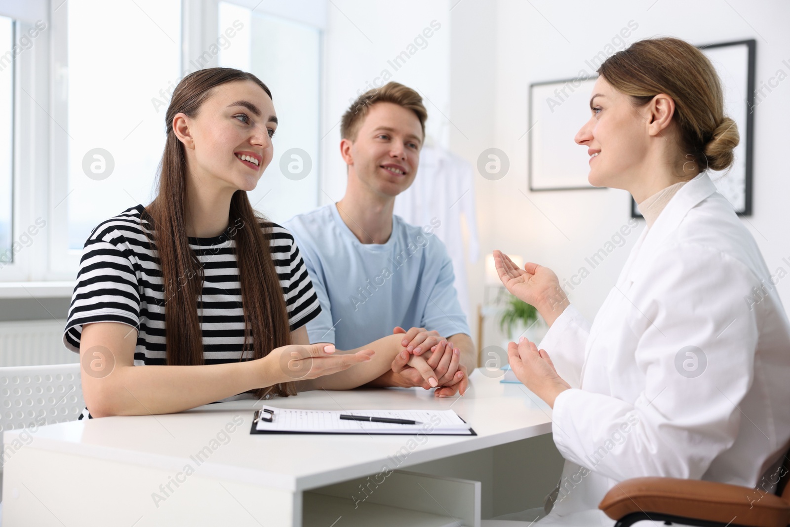 In vitro fertilization (IVF). Happy couple having appointment with doctor in reproductive clinic Photo of In vitro fertilization (IVF). Happy couple having appointment with doctor in reproductive clinic