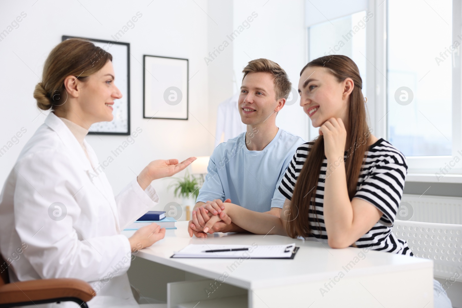 Photo of In vitro fertilization (IVF). Happy couple having appointment with doctor in reproductive clinic