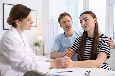 Photo of In vitro fertilization (IVF). Doctor encouraging couple during visit in reproductive clinic